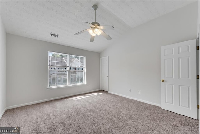 carpeted spare room featuring visible vents, ceiling fan, baseboards, vaulted ceiling, and a textured ceiling