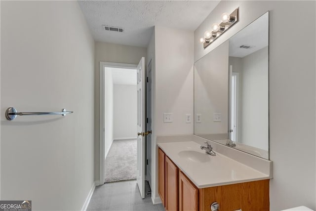 bathroom with visible vents, baseboards, a textured ceiling, and vanity