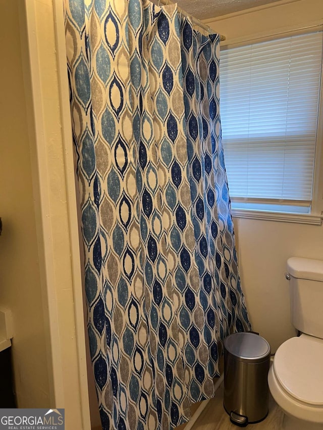 bathroom featuring walk in shower and toilet