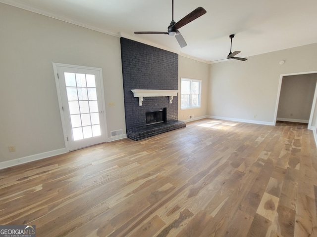 unfurnished living room featuring a brick fireplace, ceiling fan, light wood-type flooring, and ornamental molding