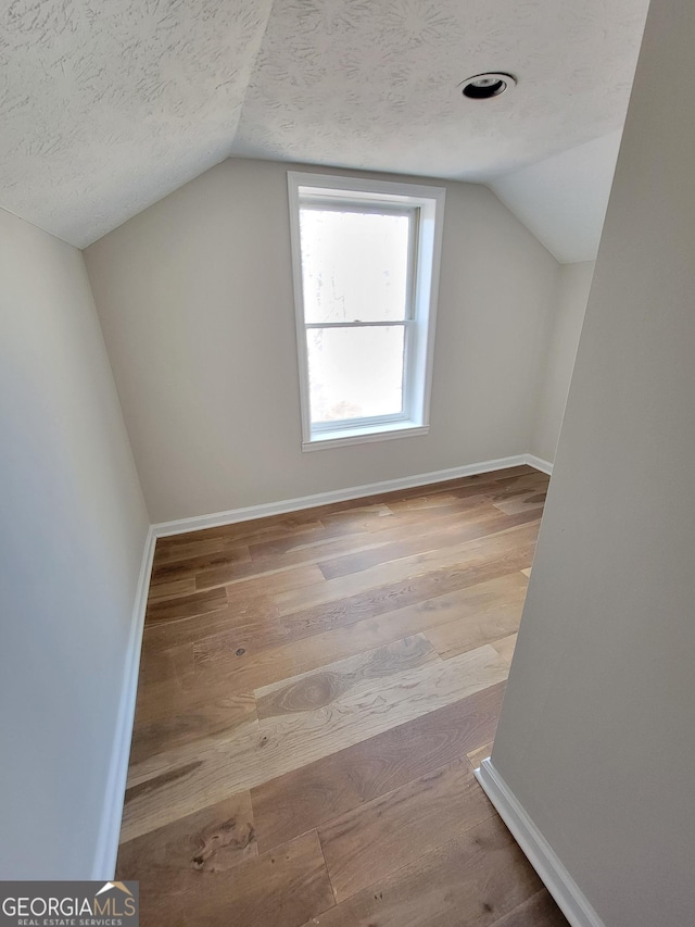 275 Allie Dr, Mcdonough, GA 30252 - bonus room featuring vaulted ceiling, wood finished floors, baseboards, and a textured ceiling