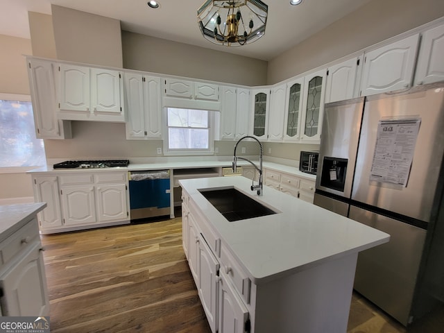 kitchen featuring stainless steel appliances, white cabinetry, and a kitchen island with sink