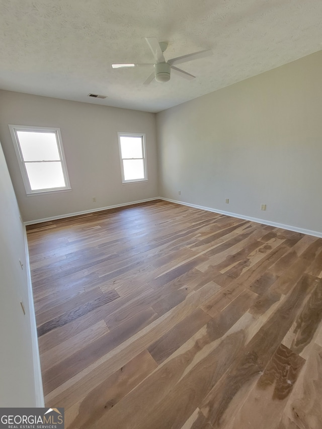 spare room with a textured ceiling, wood-type flooring, and ceiling fan