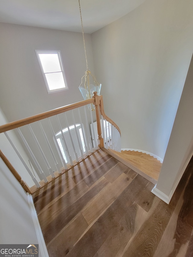 stairway with hardwood / wood-style floors and a chandelier