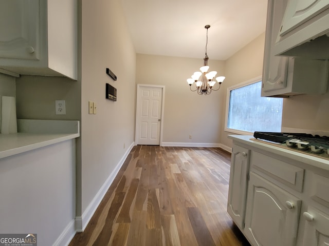 kitchen featuring white gas stovetop, hardwood / wood-style flooring, decorative light fixtures, and a notable chandelier