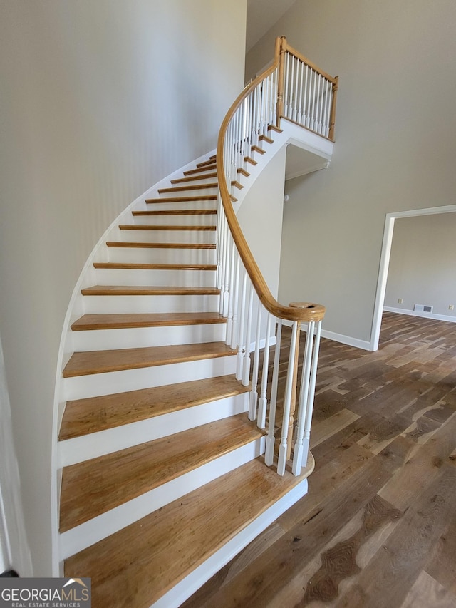 275 Allie Dr, Mcdonough, GA 30252 - stairs featuring wood finished floors, a towering ceiling, and baseboards