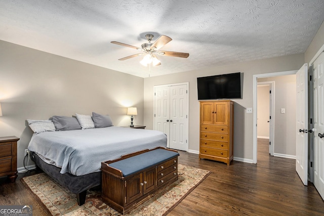 bedroom with a textured ceiling, ceiling fan, dark wood-type flooring, and a closet