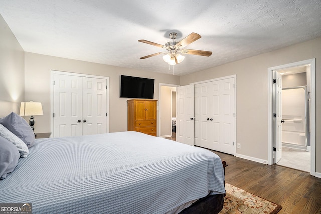 bedroom with ensuite bathroom, a textured ceiling, ceiling fan, dark hardwood / wood-style floors, and multiple closets