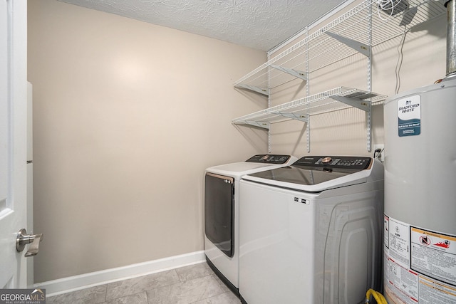 laundry area featuring light tile patterned flooring, a textured ceiling, washing machine and dryer, and water heater