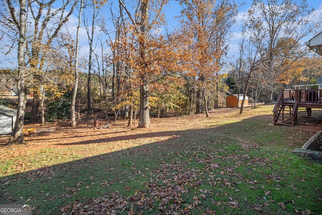 view of yard featuring a wooden deck and a storage unit