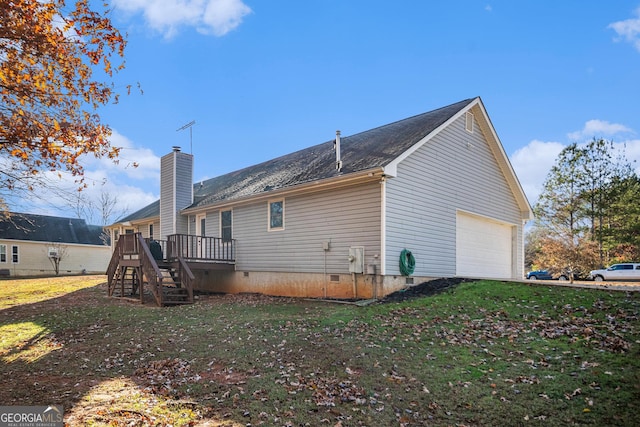 rear view of house featuring a lawn, a garage, and a deck