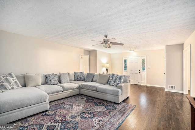 living room with a textured ceiling, dark hardwood / wood-style flooring, and ceiling fan