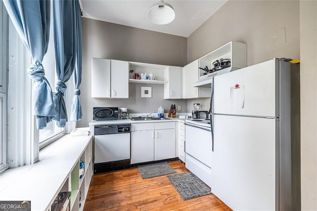 kitchen featuring hardwood / wood-style floors, white appliances, white cabinetry, and sink