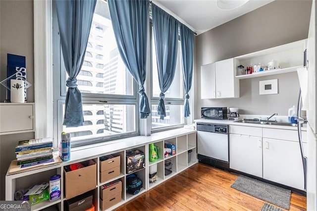 kitchen featuring hardwood / wood-style floors, white cabinetry, sink, and dishwasher