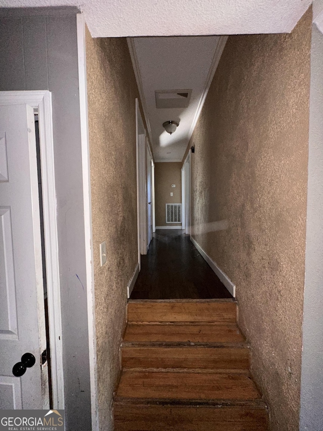 stairs featuring crown molding, a textured ceiling, and hardwood / wood-style flooring