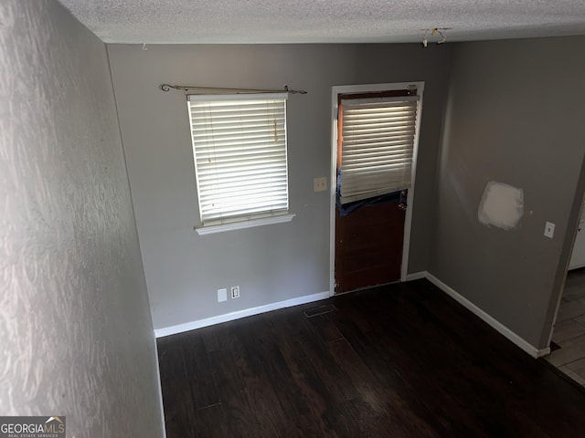 spare room featuring dark wood-type flooring and a textured ceiling