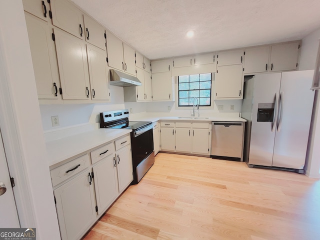 kitchen with a textured ceiling, sink, light wood-type flooring, and appliances with stainless steel finishes