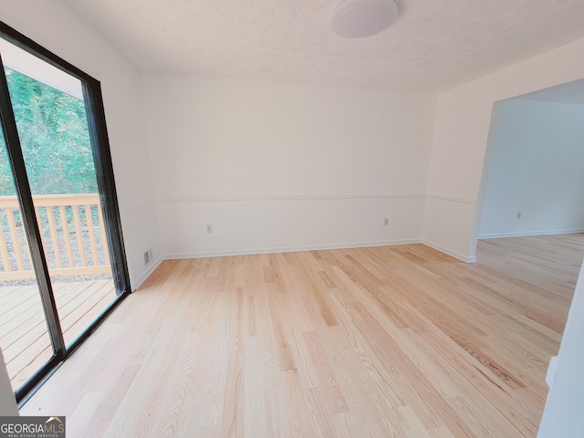 spare room featuring light hardwood / wood-style flooring and a textured ceiling