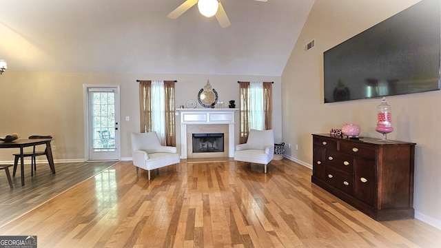 living room with ceiling fan, light hardwood / wood-style flooring, and lofted ceiling