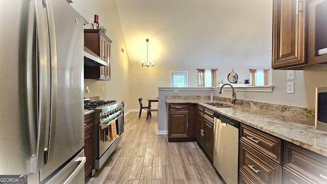 kitchen with sink, a notable chandelier, dark brown cabinets, light hardwood / wood-style floors, and stainless steel appliances