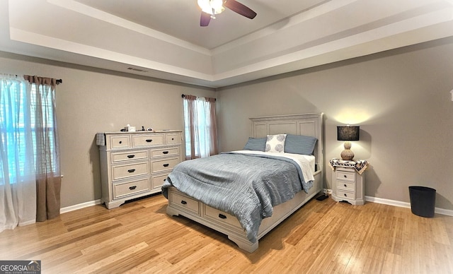 bedroom featuring a tray ceiling, ceiling fan, and light hardwood / wood-style flooring