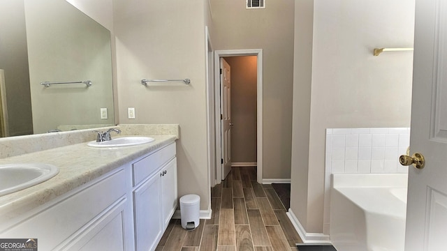 bathroom with a tub to relax in, vanity, and wood-type flooring