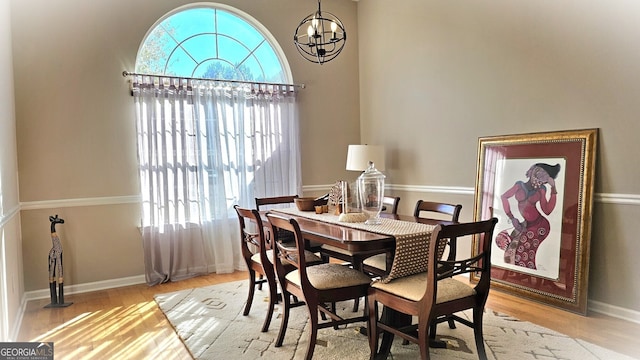 dining room with light wood-type flooring, plenty of natural light, and a notable chandelier