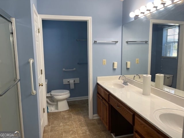 bathroom with toilet, vanity, and a shower with door