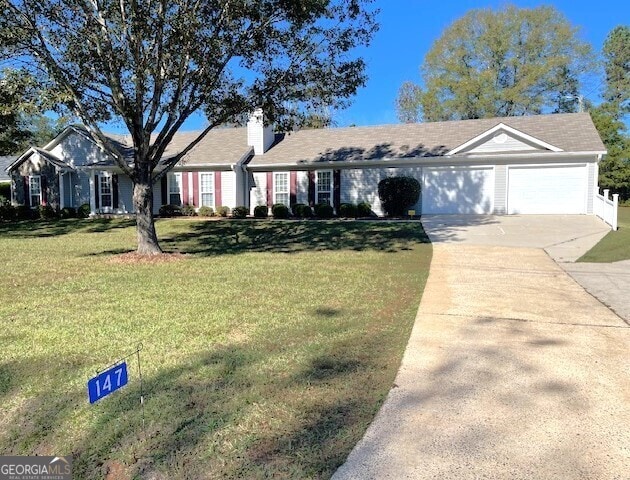 ranch-style house featuring a garage and a front lawn