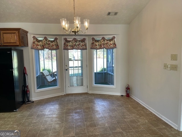 unfurnished dining area with a chandelier and a textured ceiling