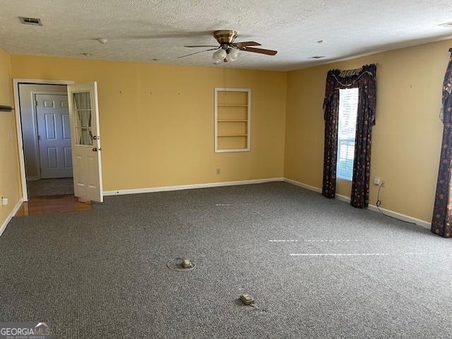 empty room featuring ceiling fan, dark colored carpet, and a textured ceiling