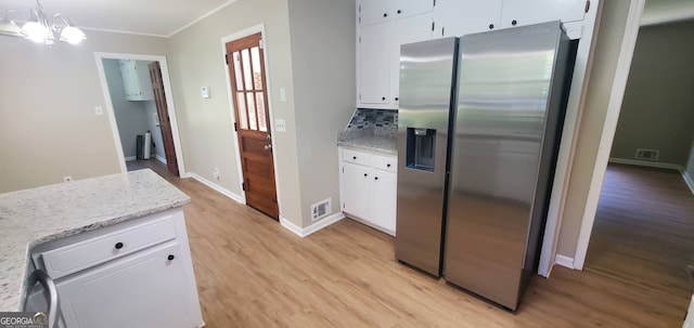 kitchen featuring tasteful backsplash, white cabinetry, pendant lighting, and stainless steel fridge