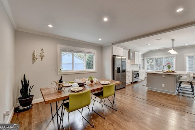 dining room with crown molding, sink, light hardwood / wood-style flooring, and lofted ceiling