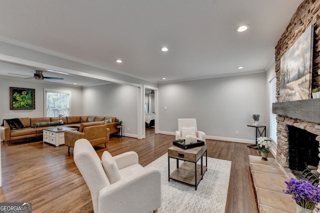 living room featuring hardwood / wood-style floors, ceiling fan, a fireplace, and crown molding