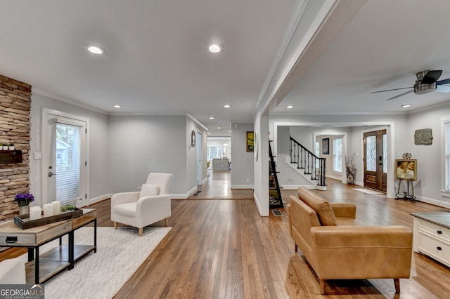 living room with light hardwood / wood-style floors, ceiling fan, and crown molding