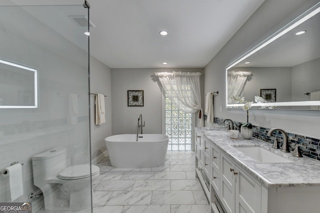 bathroom featuring vanity, a bathing tub, decorative backsplash, and toilet