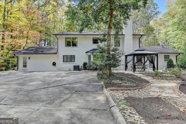 back of house with central AC unit and a gazebo