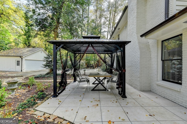 view of patio / terrace featuring a garage, an outdoor structure, and a gazebo