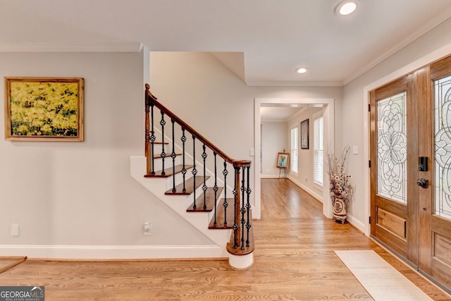 foyer featuring light wood-type flooring and crown molding