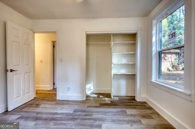 unfurnished bedroom with multiple windows, a closet, and hardwood / wood-style flooring