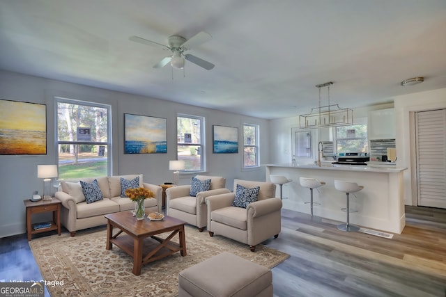 living room with ceiling fan, light wood-type flooring, and sink