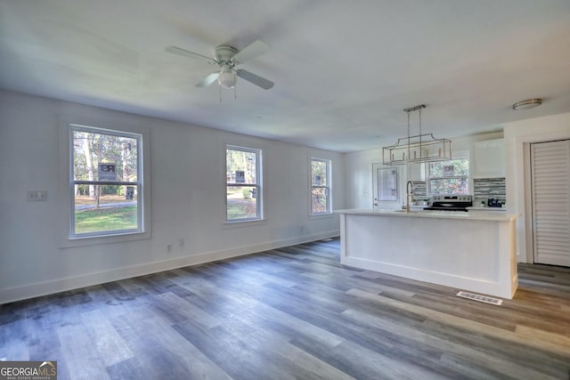 kitchen featuring plenty of natural light, white cabinetry, sink, and decorative light fixtures