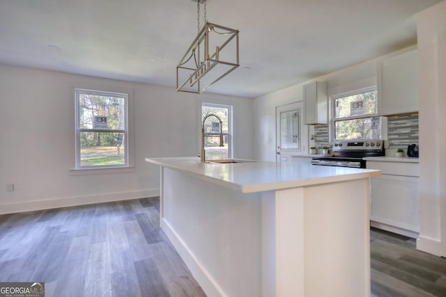 kitchen featuring backsplash, stainless steel range with electric stovetop, a kitchen island, white cabinetry, and hanging light fixtures