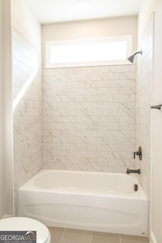 bathroom with tiled shower / bath, tile patterned floors, and toilet