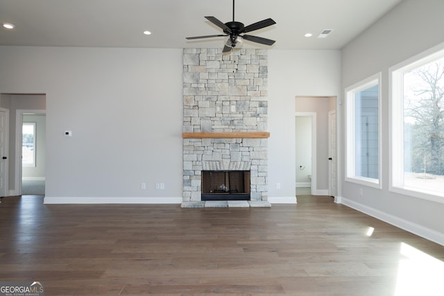 unfurnished living room with ceiling fan, wood-type flooring, a fireplace, and a wealth of natural light