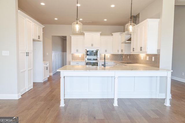 kitchen with pendant lighting, appliances with stainless steel finishes, light hardwood / wood-style floors, and white cabinets