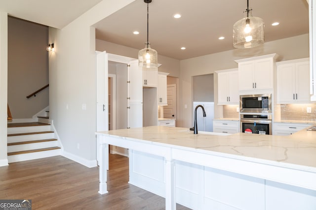 kitchen with stainless steel appliances, white cabinetry, decorative backsplash, and decorative light fixtures