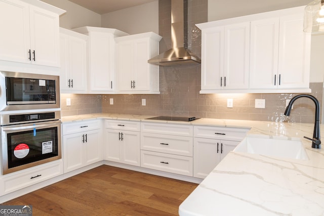 kitchen with sink, oven, backsplash, and wall chimney exhaust hood