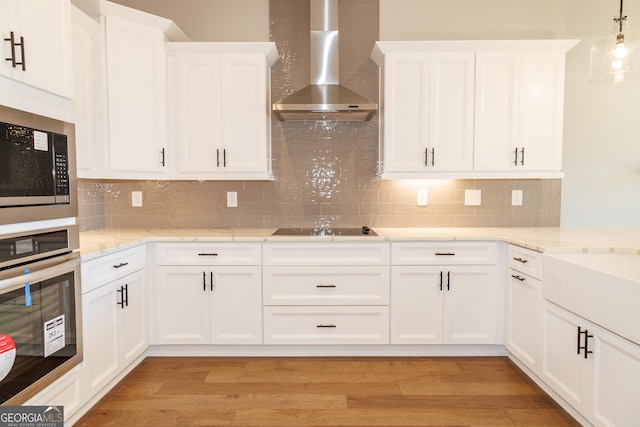 kitchen with black appliances, decorative backsplash, and wall chimney exhaust hood