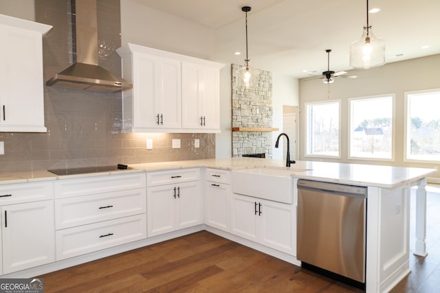 kitchen with wall chimney range hood, sink, dishwasher, white cabinetry, and tasteful backsplash